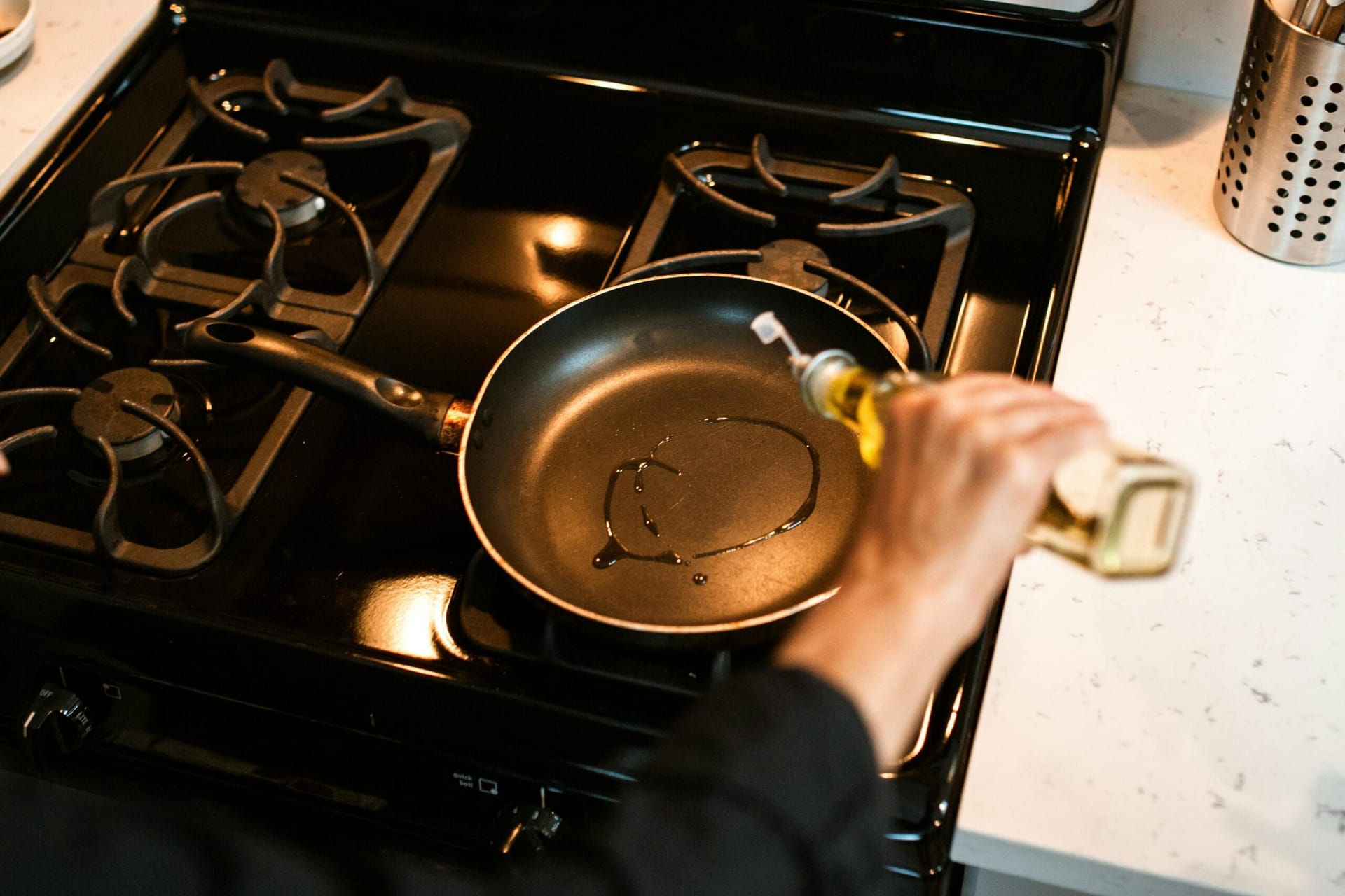 Person pouring oil in pan